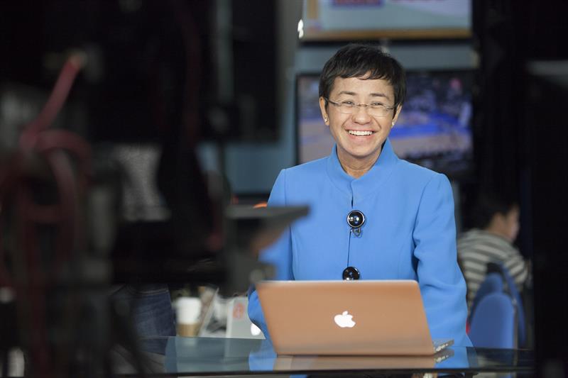 Journalist Maria Ressa sitting at a laptop in a newsroom